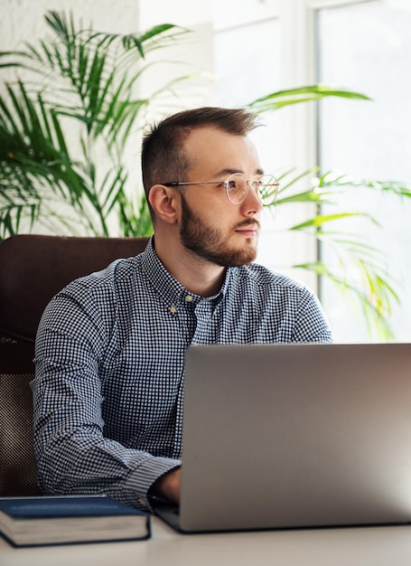 Jeune homme d'affaires en chemise travaillant sur son ordinateur portable dans un bureau