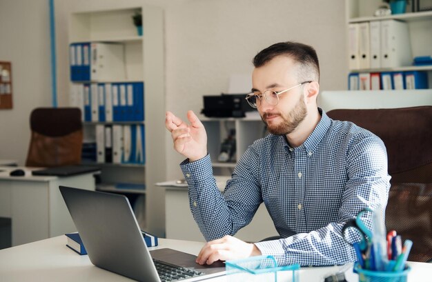 Jeune homme d'affaires en chemise travaillant sur son ordinateur portable dans un bureau