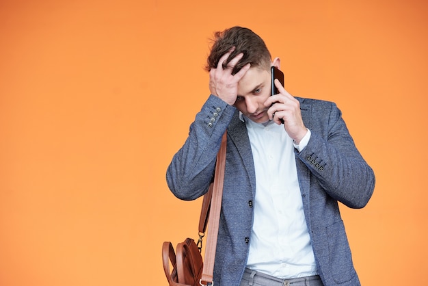 Jeune homme d'affaires choqué et stressé recevant de mauvaises nouvelles au téléphone