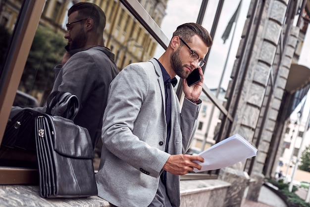 Jeune homme d'affaires de communications d'affaires se penchant sur le mur sur la rue de ville parlant dessus