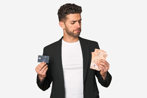 Jeune homme d'affaires comparant les méthodes de paiement détenant des euros dans une main et une carte de crédit dans l'autre