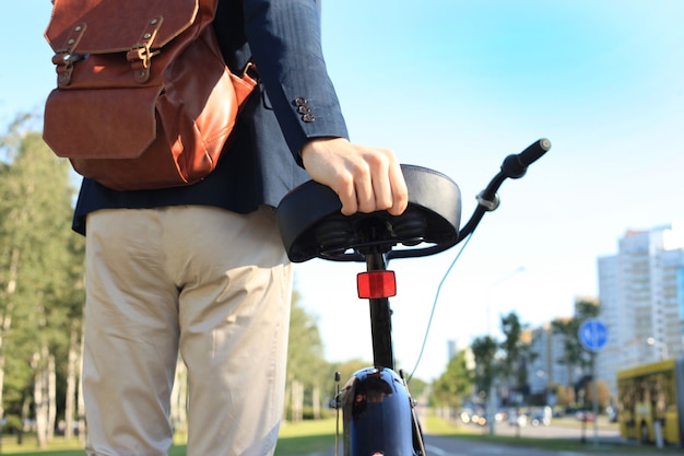 Jeune homme d'affaires confiant marchant à vélo dans la rue en ville.