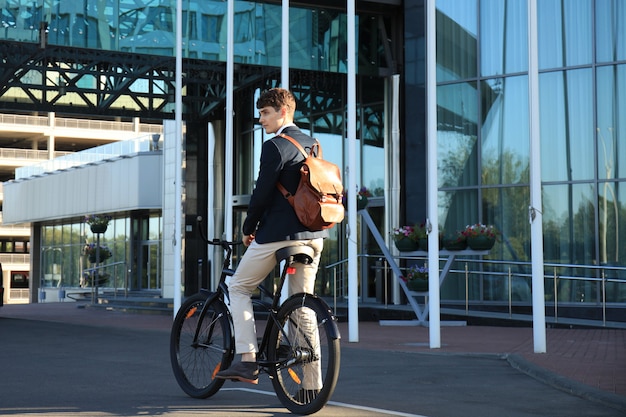 Jeune homme d'affaires confiant marchant à vélo dans la rue en ville.