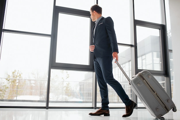 Jeune homme d'affaires en costume marche dans le hall de l'aéroport