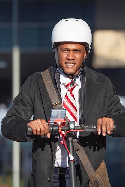 Jeune homme d'affaires en costume sur un scooter électrique regardant la caméra Concept de transport écologique