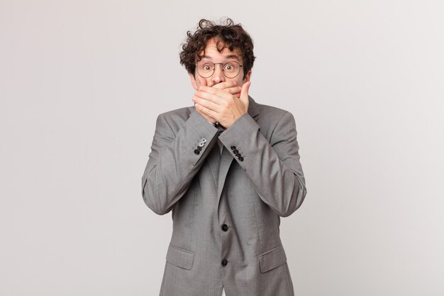 Jeune homme d'affaires couvrant la bouche avec les mains avec un choc