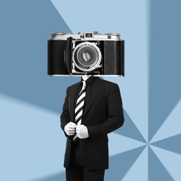 Un jeune homme d'affaires dans un costume noir dirigé par un énorme vieil appareil photo rétro vintage