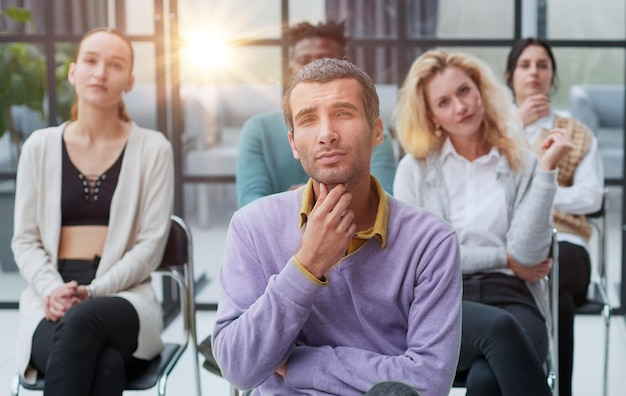 Un jeune homme d'affaires dans un pull violet est assis contre le fond de ses collègues dans un moderne de