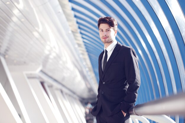 Jeune homme d'affaires debout dans le couloir de l'immeuble de bureaux moderne