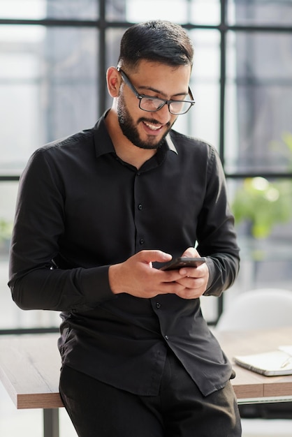 Jeune homme d'affaires décontracté tenant et utilisant un smartphone pour les messages sms