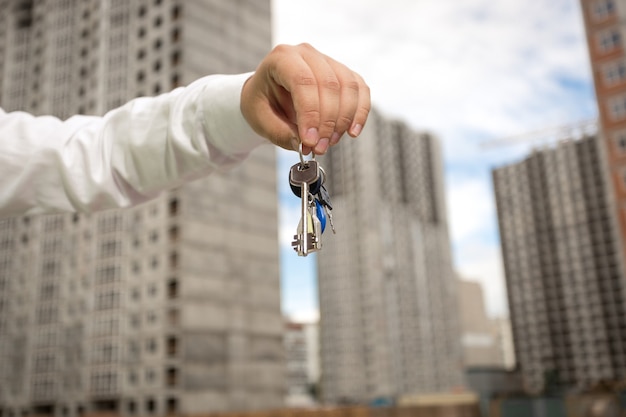 Jeune homme d'affaires détenant des clés de nouveaux biens immobiliers sur le chantier