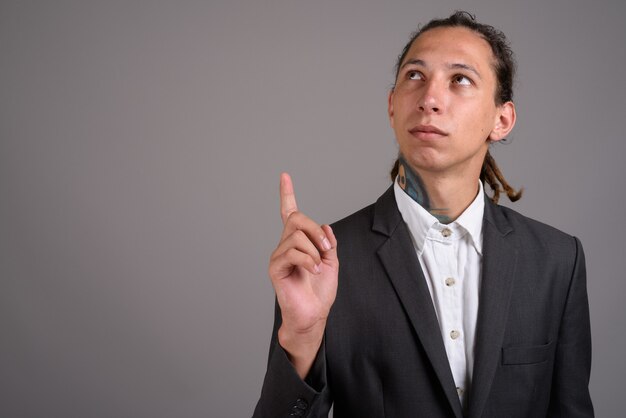 Jeune homme d'affaires avec des dreadlocks sur fond gris