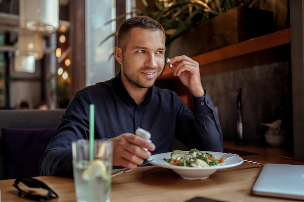 Un jeune homme d'affaires écoute de la musique tout en déjeunant au restaurant