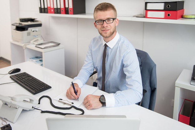 Jeune homme d'affaires écrivant une lettre Notes ou correspondance ou signant un document ou un accord