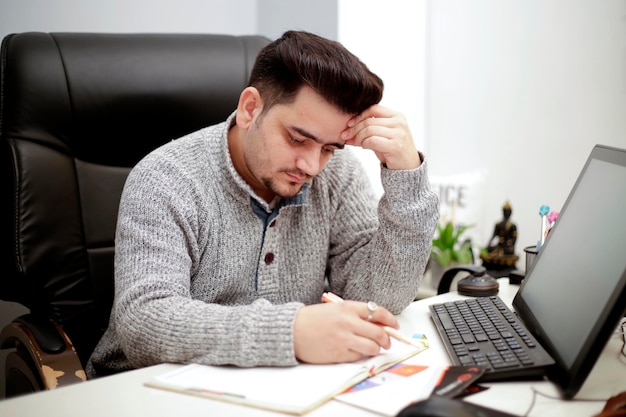 Un jeune homme d'affaires est stressé et lit le journal.