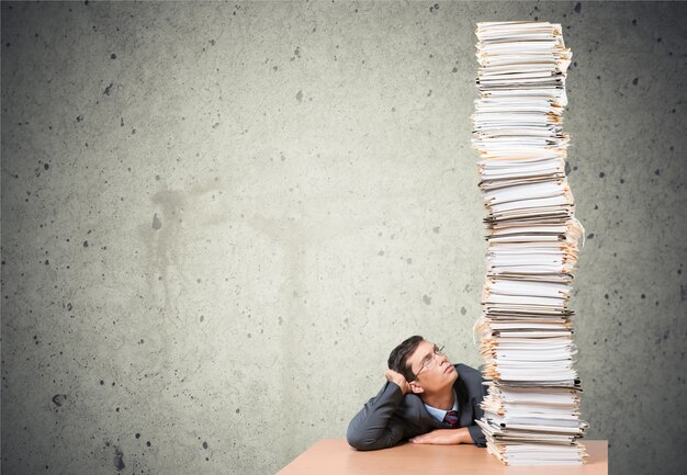 Jeune homme d'affaires fatigué avec une pile de papiers