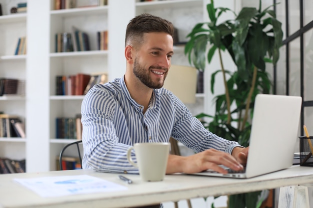 Un jeune homme d'affaires heureux analyse des documents financiers depuis son domicile pendant l'auto-isolement.