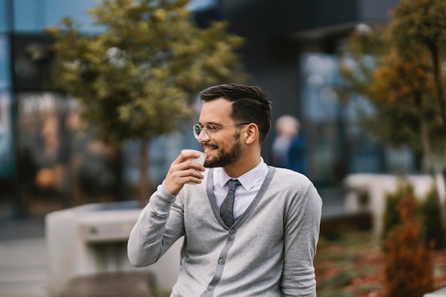 Un jeune homme d'affaires heureux appréciant le café dehors