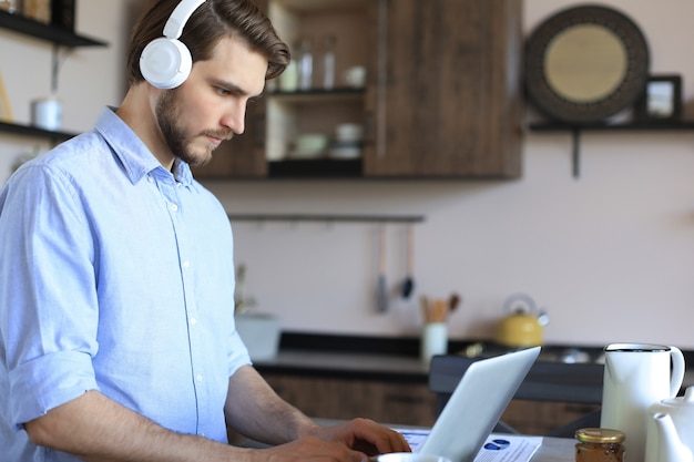 Jeune homme d'affaires indépendant concentré utilisant un ordinateur portable pour la vidéoconférence, travaillant à distance en ligne à la maison.