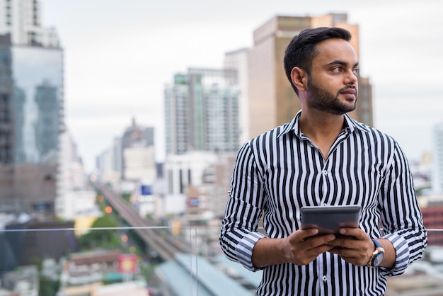 Jeune homme d'affaires indien barbu contre vue sur la ville