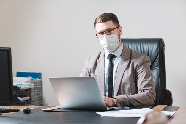 Jeune homme d'affaires à lunettes et masque facial au bureau