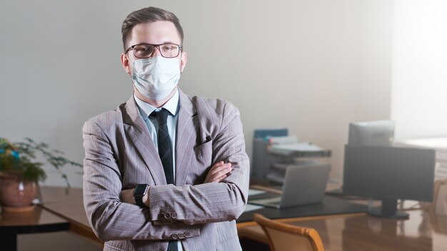 Jeune homme d'affaires à lunettes et masque facial au bureau