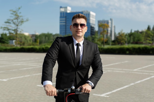 Jeune homme d'affaires à lunettes de soleil sur un scooter électrique dans la ville