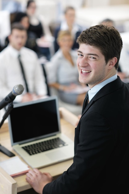 jeune homme d'affaires masculin donnant une présentation lors d'un séminaire de réunion dans une salle de conférence moderne sur un plateau de table