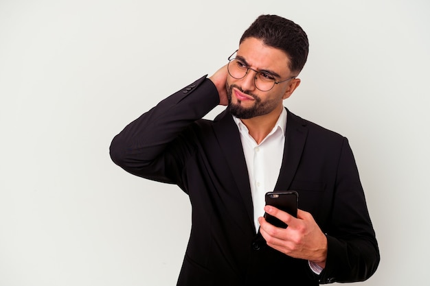 Jeune homme d'affaires métisse tenant un homme de téléphone portable isolé sur fond blanc, toucher l'arrière de la tête, penser et faire un choix.