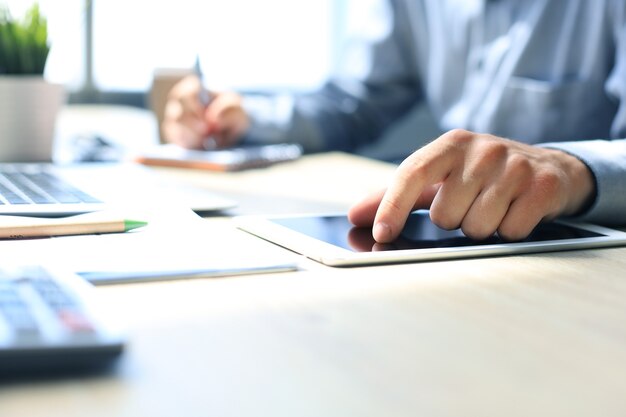 Jeune homme d'affaires moderne travaillant à l'aide d'une tablette numérique alors qu'il était assis au bureau.