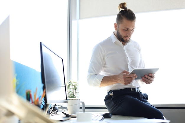 Jeune homme d'affaires moderne travaillant à l'aide d'une tablette numérique alors qu'il était assis au bureau.