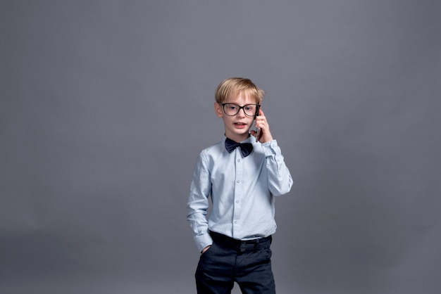 Photo jeune homme d'affaires, parler au téléphone. petit garçon posant sur un gris