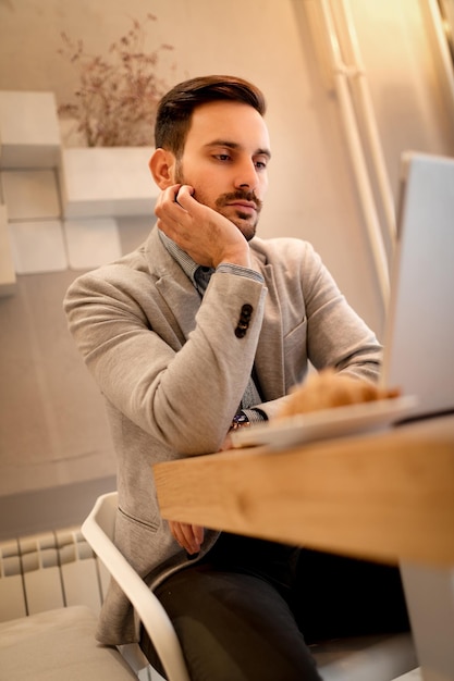 Jeune homme d'affaires pensif en pause dans un café. Il travaille sur un ordinateur portable.