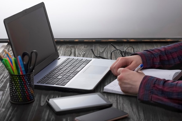 Jeune homme d'affaires ou pigiste travaillant avec des documents et avec un bureau à distance pour ordinateur portable et smartphone