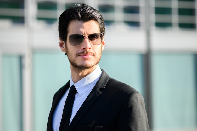 Jeune homme d'affaires en plein air portant des lunettes de soleil