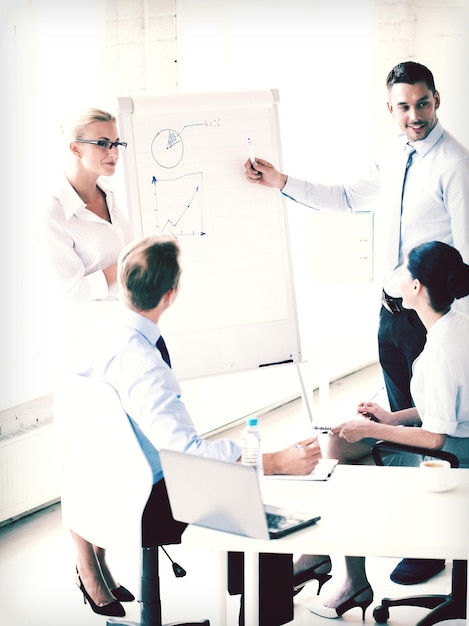 jeune homme d'affaires pointant sur graphique sur flip board in office