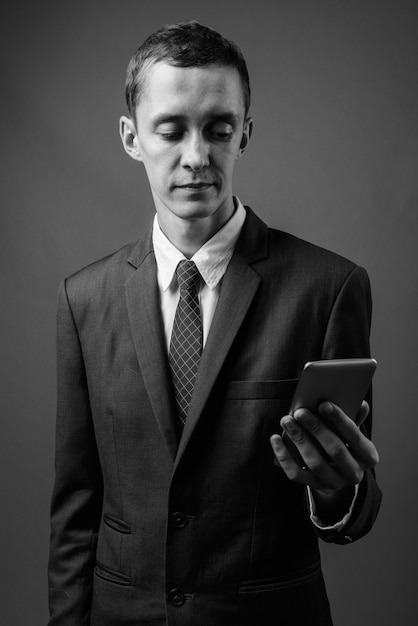 jeune homme d'affaires portant un costume contre un mur gris en noir et blanc