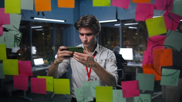 Un jeune homme d'affaires prend une photo de notes sur une planche de verre au bureau