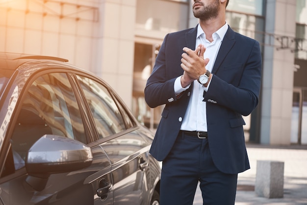 Jeune homme d'affaires près d'une nouvelle voiture en attente d'une réunion