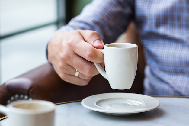 Jeune homme d'affaires prospère assis dans un café et buvant du café du matin. Composition de style de vie avec lumière naturelle