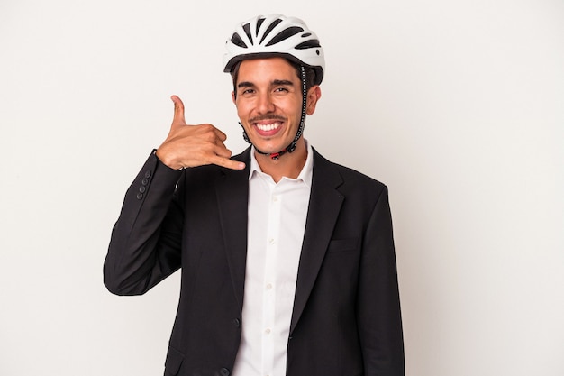 Jeune homme d'affaires de race mixte portant un casque de vélo isolé sur fond blanc montrant un geste d'appel de téléphone portable avec les doigts.