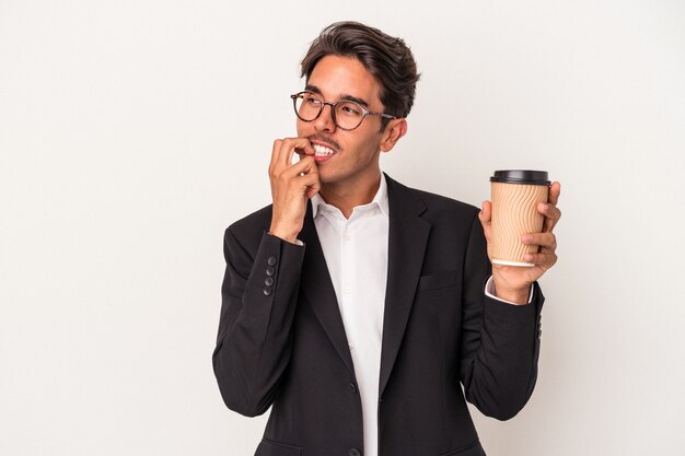 Jeune homme d'affaires de race mixte tenant du café à emporter isolé sur fond blanc détendue en pensant à quelque chose en regardant un espace de copie.