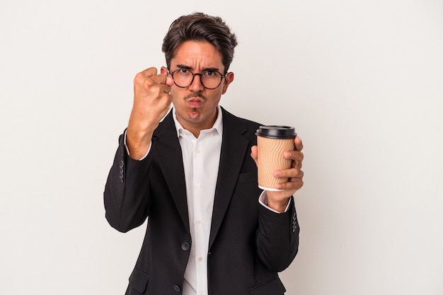 Jeune homme d'affaires de race mixte tenant du café à emporter isolé sur fond blanc montrant le poing à la caméra, expression faciale agressive.