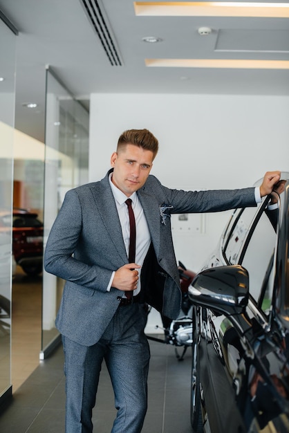 Un jeune homme d'affaires regarde une nouvelle voiture chez un concessionnaire automobile. Acheter une voiture.