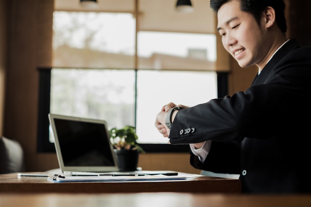 Jeune homme d&#39;affaires regarde smart montre-bracelet au bureau, concept d&#39;affaires