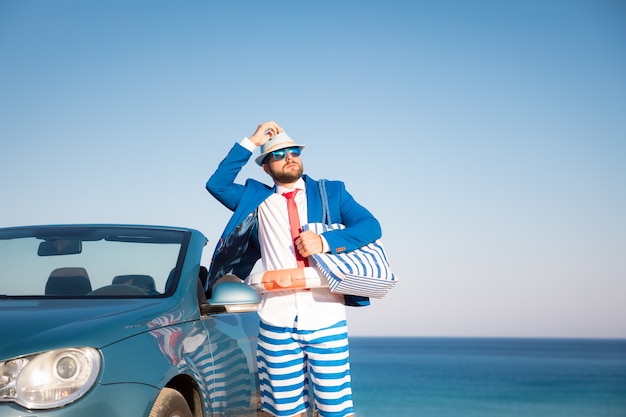 Jeune homme d'affaires réussi sur une plage Homme debout dans la voiture classique cabriolet