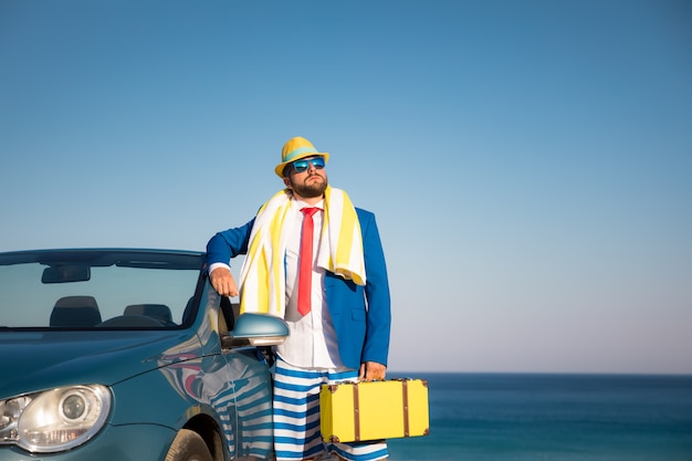 Jeune homme d'affaires réussi sur une plage Homme debout dans la voiture classique cabriolet