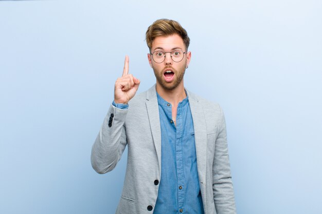 Jeune homme d'affaires se sentant comme un génie heureux et excité après avoir réalisé une idée, levant joyeusement le doigt, eureka!