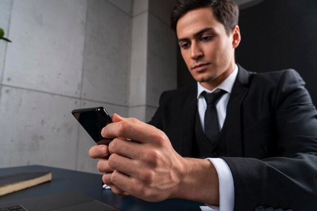 Jeune homme d'affaires sérieux utilisant le téléphone au bureau