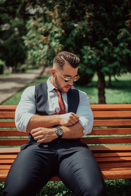 Un jeune homme d'affaires sexy en costume assis dans un parc en pause de travail